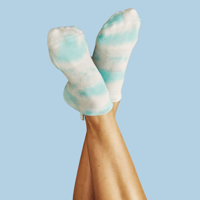 arctic A pair of legs in white socks, featuring colorful blue tie-dye, positioned casually on a comfortable surface.