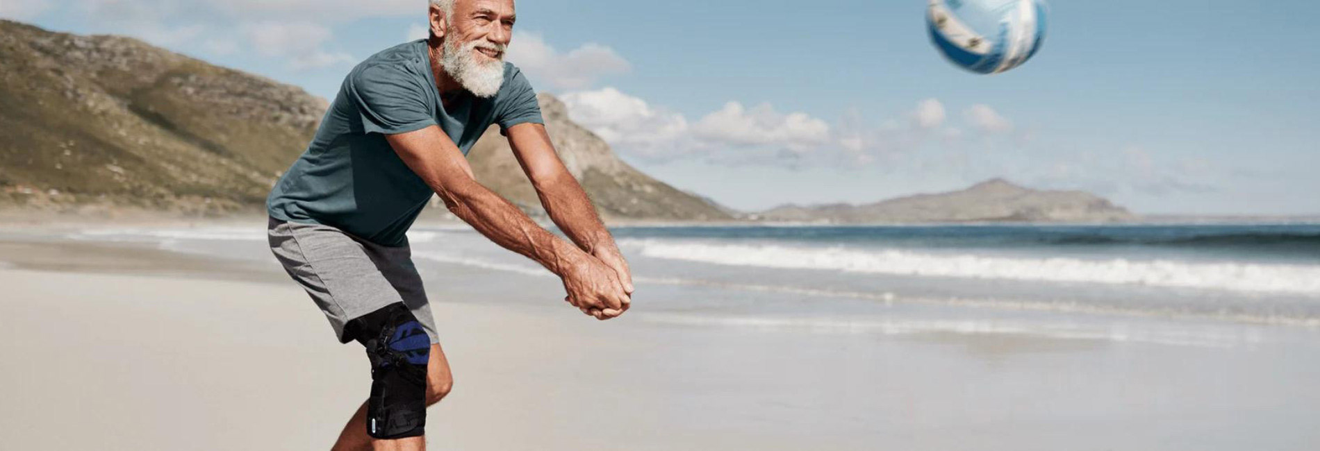 Man wearing a kneee brace playing beach volleyball