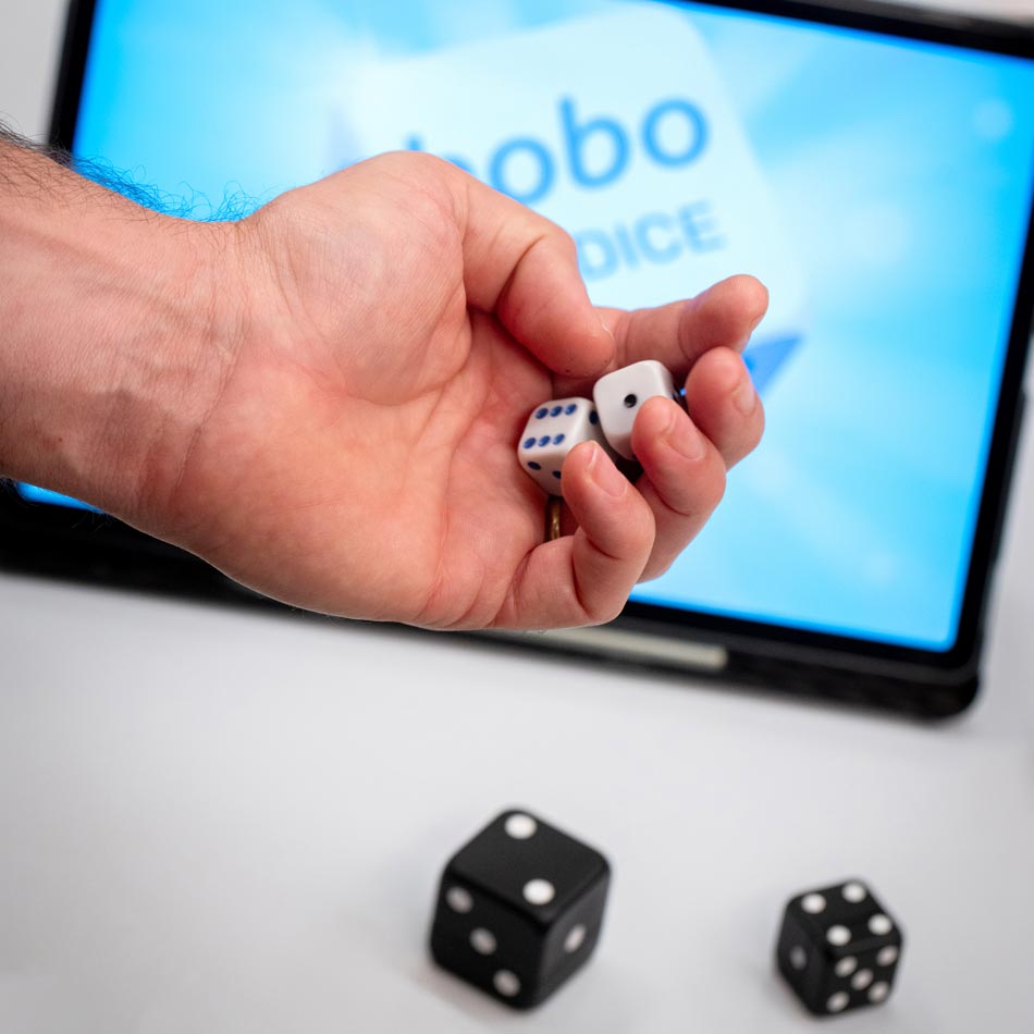 VAVO0164 A person holding a dice in front of a laptop, ready for a game of chance and excitement