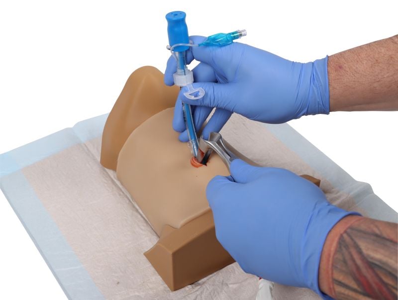 image5 A person in blue gloves injecting a syringe into a dummy with a needle