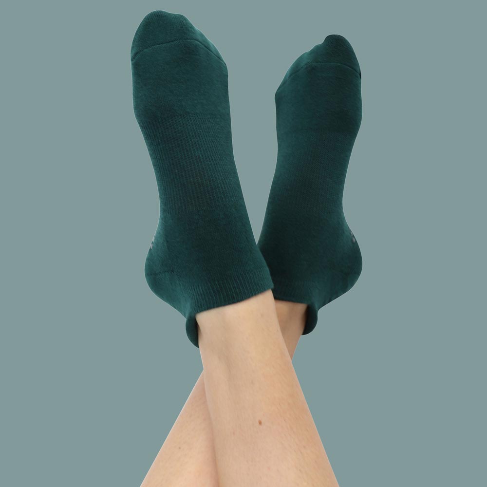 Sacramento-Main Two legs in vibrant green socks, casually positioned on a cozy background, showcasing the playful color.